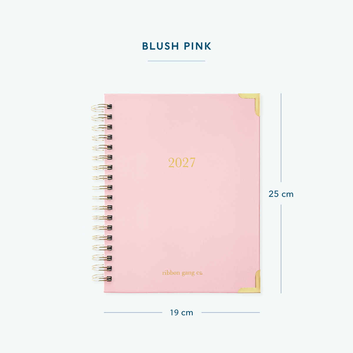 A blush pink spiral bound 2027 planner with gold lettering and gold corners on a white background showing dimensions of 25 cm high and 19 cm wide.
