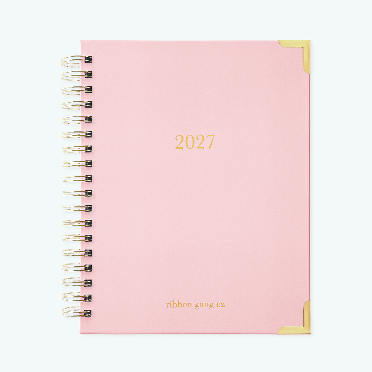 A blush pink spiral bound 2027 planner with gold lettering and gold corners on a white background.
