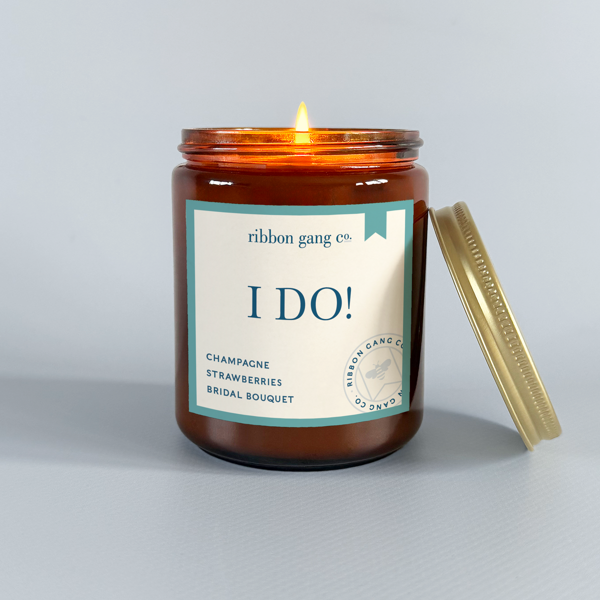 Candle in an amber jar with an "I Do!" label on a gray background.
