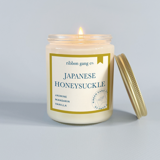 Candle with 'Japanese Honeysuckle' label on a grey background.